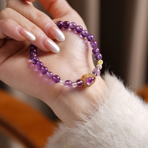 Detail of purple crystal beaded bracelet with heart pendant on model's wrist