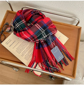 Macro detail of plaid cashmere feel scarf with fringe tassels on a wooden tray
