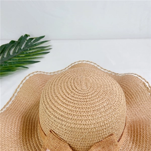 Dettaglio ravvicinato di cappello di paglia beige pieghevole con trama intrecciata e fiocco