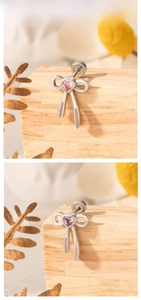 Detail von silbernen Schleifenohrringen mit rosa und lila herzförmigen Edelsteinen