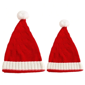 Detail of red and white knitted Christmas hats with faux fur pom poms for mother and child