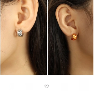 Detailed close-up of gold and silver C-shaped titanium earrings with quilted pattern