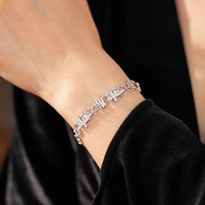 Detail of silver chain bracelet with clear zircon stones on a model wrist with black velvet background