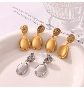 Detailed view of gold and silver water drop earrings with rhinestones on ceramic tray