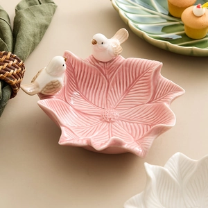 Pink ceramic flower shaped jewelry soap dish featuring decorative birds on a beige surface