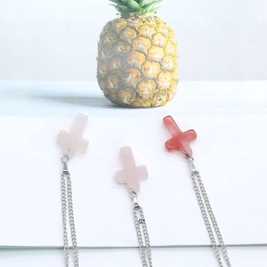 Detailed view of three cross pendants crafted from rose quartz and red agate on silver chains