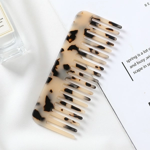 Close-up of wide-tooth acetate hair comb with classic tortoiseshell pattern on silk fabric