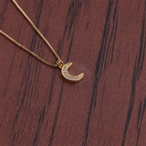Macro shot of gold crescent moon necklace with clear zircons on wood surface