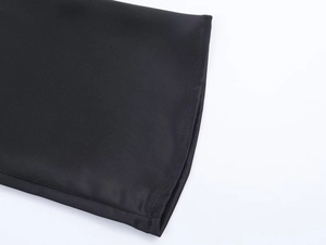 Detailed close-up of smooth satin fabric texture and neat stitching on black dress hem