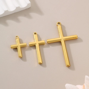 Three sizes of polished golden titanium steel cross pendants on a decorative background
