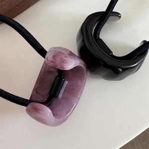 Detail of purple marble and black resin hair rings with elastic bands on white surface