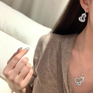 Detail of silver heart necklace and earrings set with light blue and clear zircons