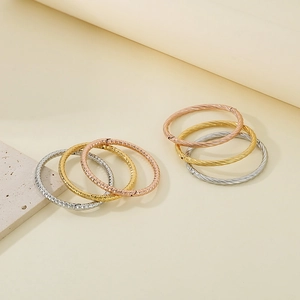 Detail of twisted and hammered textured metal bangles in silver, gold, and rose gold