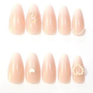 Macro detail of almond press-on nails with 3D teddy bear, pearls and heart accents