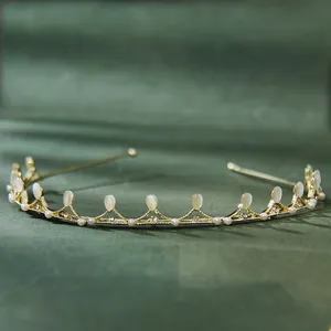 Detailed shot of golden leaf headband with cat-eye stones and pearls on green fabric