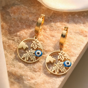 Golden evil eye hoop earrings with leaf detail and blue stone on white silk