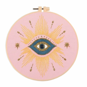 Completed evil eye embroidery kit in a wooden hoop with gold and blue threads