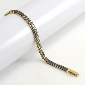 Detail of gold tennis bracelet with rectangular black cubic zirconia around white stand