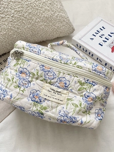 Quilted blue floral makeup bag with top handle and dual zippers for travel storage