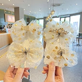 Detail of children's sequined bow hair clip with lace netting and small gold crown
