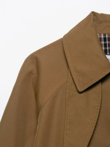 Detailed close-up of the khaki trench coat collar and classic plaid lining texture