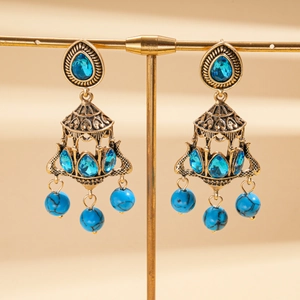 Macro shot of vintage gold earrings with blue stones and marble textured beads