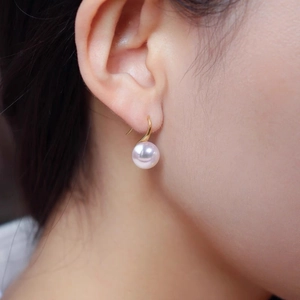 Elegant pink faux Mabe pearl earrings with gold hooks worn by a model in a close-up view