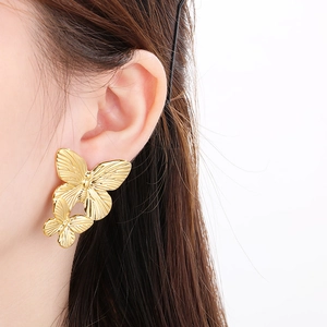 Minimalist gold butterfly stud earrings with vintage texture shown on female model