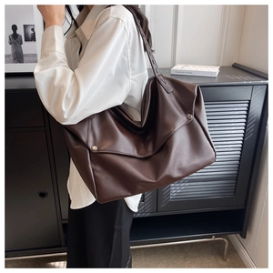 Detail view of large dark brown leather tote bag with lychee texture and metal rivets