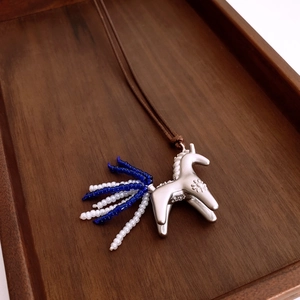 Detailed macro of S925 sterling silver pony pendant with blue beads on wood