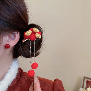 Detail of red pompom hair clip with golden sycee and long tassel on dark hair