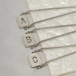 Detailed macro view of square alphabet pendants A B C with frosted glitter finish