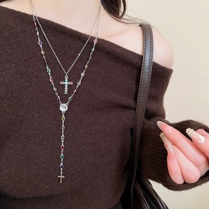 Detail of silver double-layered cross necklace set with multi-colored gemstones