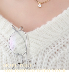 Close-up of gold chain necklace with round white zircon pendant on knitted sweater