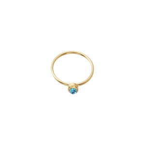 Detail view of a slim gold-plated ring with a faceted round light blue birthstone inlay