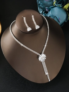 Close-up of silver floral rhinestone necklace and tassel earring jewelry set for women