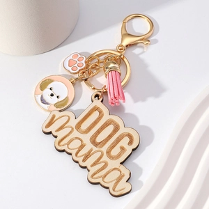 Macro detail of DOG mama wooden tag with pink tassel and paw charm on golden keychain