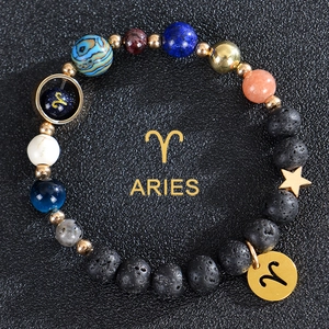 Macro detail of Aries zodiac bracelet with lava rock, blue sandstone and gold charms