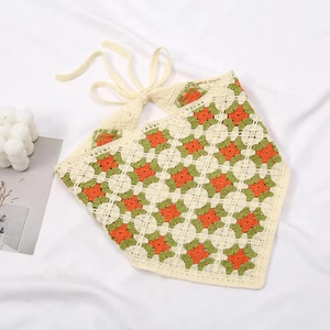 Detail of hand-crocheted cream triangle headscarf with orange and green floral patterns