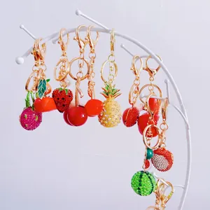 Detailed display of rhinestone fruit keychains on a metal stand featuring various fruit designs