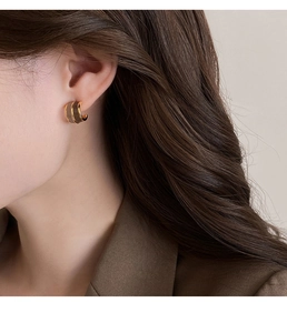 Detail of C-shaped Maillard contrast oil drop earring on model in golden finish