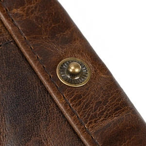 Macro shot of dark brown top grain leather texture with bronze snap button and stitching