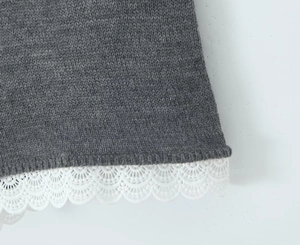 Gros plan sur la maille grise avec une délicate bordure en dentelle blanche en bas