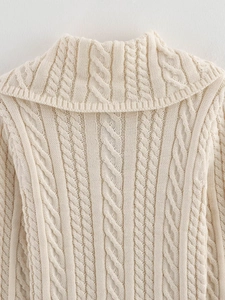 Detailed macro view of the cream cable knit sweater showing thick texture and collar