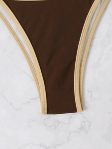 Detail of high-cut brown bikini bottom with beige contrast binding on marble background