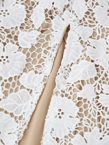 Détail de la broderie en dentelle florale blanche avec doublure beige sur une robe