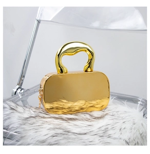 Detail of a gold acrylic mirror box bag with a curved handle on a white faux fur mat