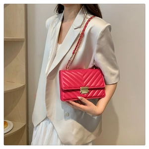 Detail of rose red chevron quilted leather crossbody bag with gold chain strap on model