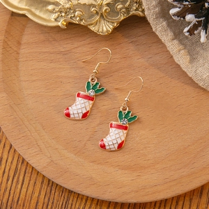 Detail of Christmas stocking drop earrings with green leaf accent on vintage background
