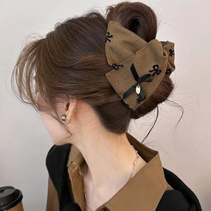 Macro detail of brown oversized fabric bow hair claw clip worn on a half-up hairstyle